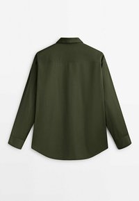 Chemise verte à manches longues avec un col classique, couture d'empiècement au dos et poignets boutonnés. Tissu lisse avec une apparence légèrement texturée.