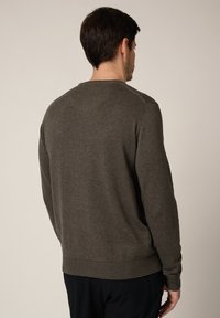 Ciemnozielony sweter z okrągłym dekoltem, ściągaczami na mankietach i dole, wykonany z miękkiego materiału. Charakteryzuje się gładką fakturą i minimalistycznym designem.