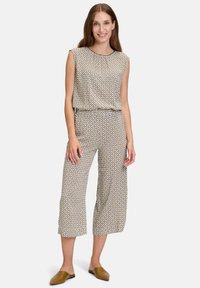 Patroon tweedelige outfit met een mouwloze top en cropped broek. Kleuren zijn crème, bruin en blauw. Gladde stoftextuur.