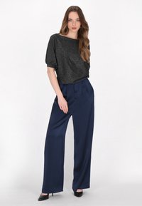 Sort, glitrende cropped top med korte ærmer, parret med højtaljede, marineblå brede bukser. Glat tekstur; slankt design; ensfarvede.