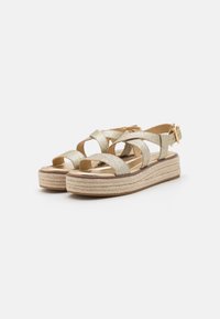 Gold glitter espadrille sandals with a cross-strap design, closed heel, and braided jute platform. Features a buckle closure on the ankle strap.