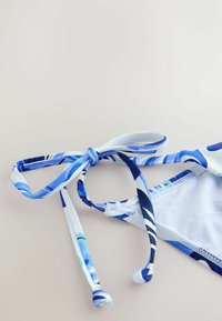 Góra od bikini z niebiesko-białym kwiatowym wzorem, regulowanymi wiązaniami i gładką tkaniną. Posiada kontrastową podszewkę wewnętrzną oraz staranne przeszycia.