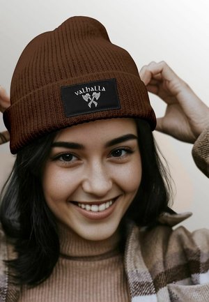 Brown knitted beanie with a folded cuff and a rectangular black patch featuring the word "valhalla" and two crossed axes.