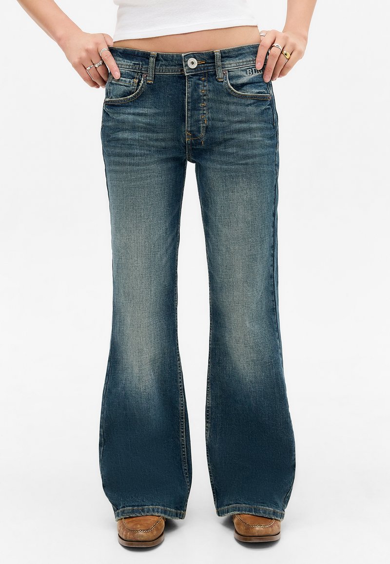 Vervaagde blauwe denim flared jeans met vijf zakken, een knoopsluiting en contrasterende stiksels. Gladde textuur met een lichte glans.
