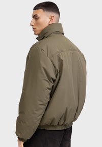 K2779_lima roheline paks bomber jope. Omab kõrget krae, elastseid mansette ja nööri allosa. Sile tekstuur minimaalsete õmblusteenuste detailidega.