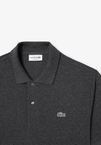 Mörkgrå polo-shirt i textilerad material, med en klassisk krage, två knappar och en vit broderad krokodil-logotyp på bröstet.