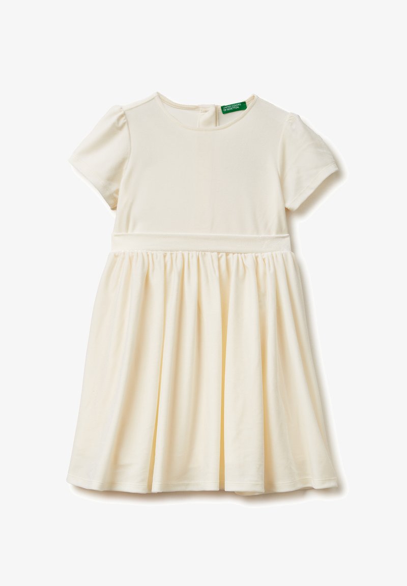 Kremowa sukienka dla dziewczynki z krótkim rękawem, z marszczonym pasem i spódnicą, okrągłym dekoltem oraz małą zieloną metką marki wewnątrz kołnierzyka.