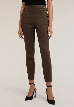 Pantalones marrones ajustados con acentos de botones laterales, que presentan una textura suave y corte slim. Combinados con zapatos de tacón alto negros.