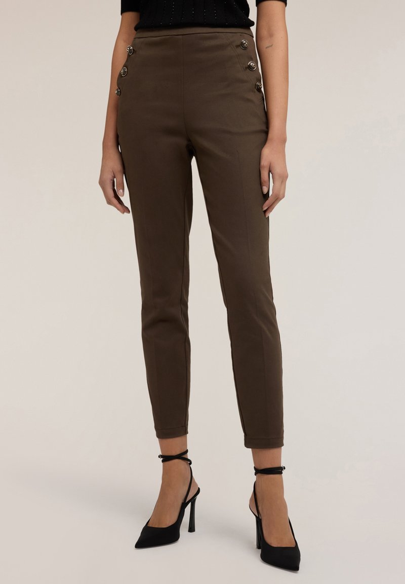 Pantaloni marroni a gamba affusolata con accenti di bottoni laterali, caratterizzati da una texture liscia e una vestibilità slim. Abbinati a scarpe nere con tacco alto.