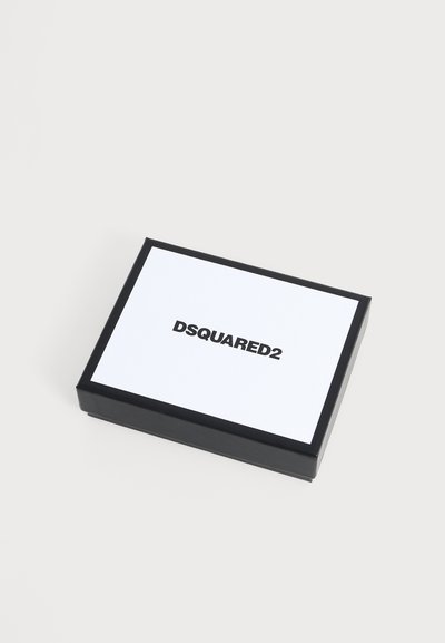 Ορθογώνιο ασπρόμαυρο κουτί με το κείμενο "DSQUARED2" τυπωμένο με μαύρα γράμματα στην άσπρη επιφάνεια στην κορυφή, τοποθετημένο σε απλό φωτεινό φόντο.