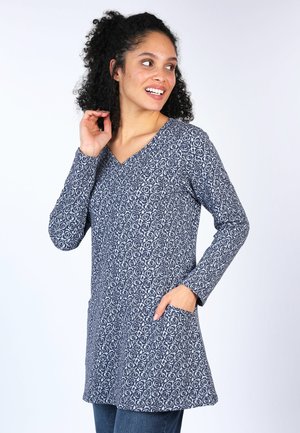 Marineblaue Tunika mit weißem Blumenmuster, V-Ausschnitt, langen Ärmeln, zwei Vorderaschen und einem leicht ausgestellt geschnittenen Saum. Weicher, strukturierter Stoff.