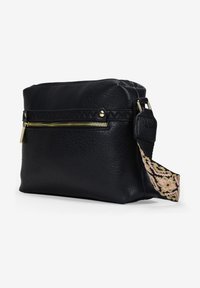 Bolso de cuero negro con superficie texturizada, que presenta un bolsillo frontal con cremallera y una correa con un patrón en rosa y negro. Forma rectangular.