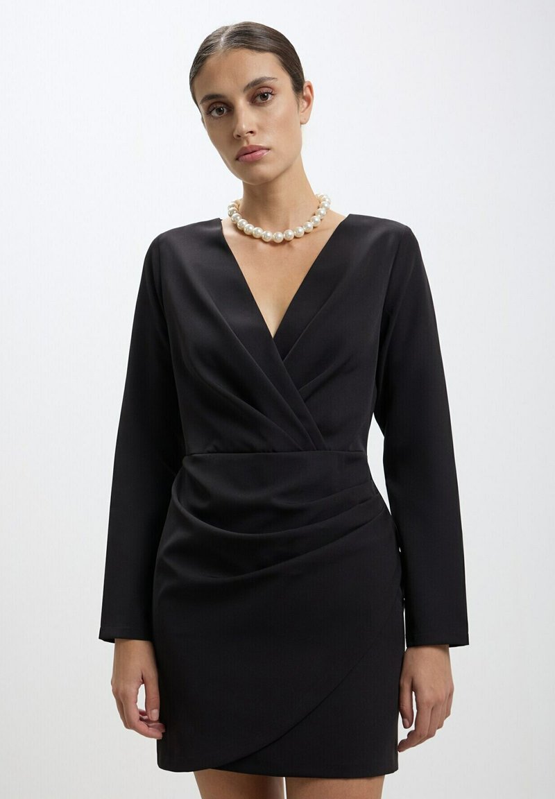 Robe noire portefeuille à manches longues, en tissu texturé, décolleté en V profond et détail froncé à la taille ; accompagnée d'un collier en perles.