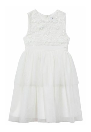 Jong meisje met krullend haar, een mouwloze witte jurk met bloemenborduurwerk en een doorschijnende gelaagde rok, gecombineerd met gouden ballerina's.