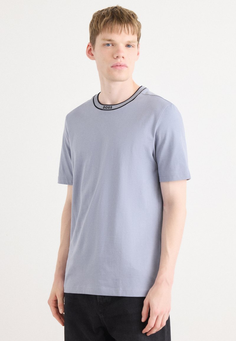 Grå kortærmet t-shirt lavet af bomuld, med en rund halsudskæring med sort kant og ordet "BOSS" broderet på.