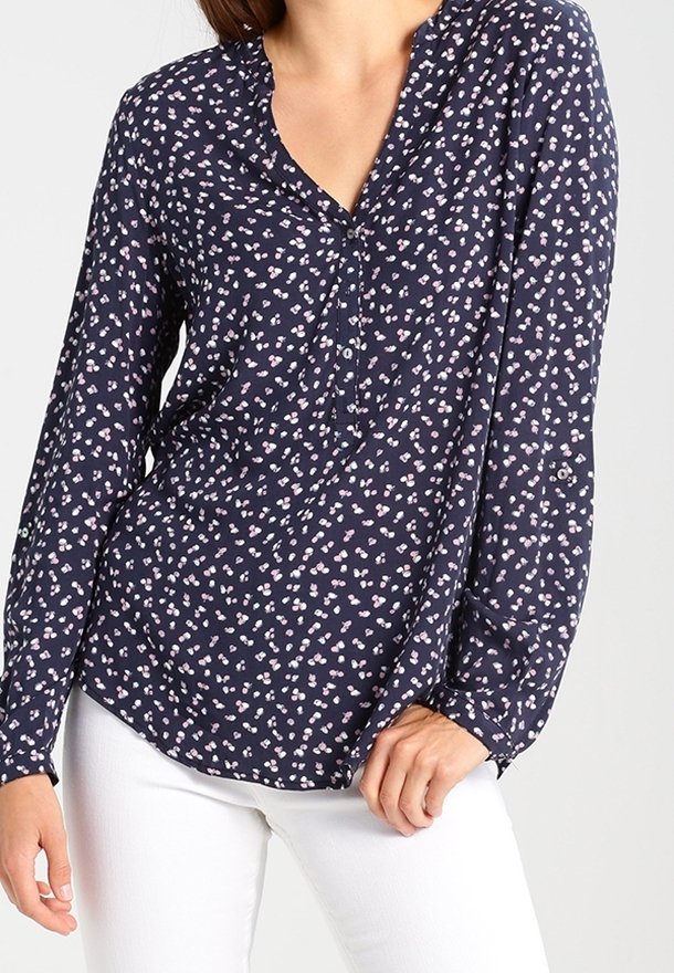 Blouse à manches longues bleu marine avec un motif floral rose et blanc, dotée d'un décolleté en V et d'une patte de boutonnage. Tissu léger, coupe ample.