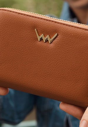 Brown leather wallet with a textured finish, gold embellishment in a zigzag pattern on the front, and a zip closure along the top edge.
