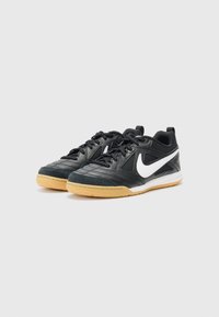 Schwarze Sportlichen Schuhe mit einer strukturierten Oberseite, weißem Nike-Swoosh und Gummisohle. Merkmale sind eine Schnürung und ein gepolsterter Schaft.
