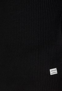 Schwarzer gerippter Strickpullover mit einer subtilen Textur und einem kleinen weißen Etikett mit "JACK & JONES" unten links.