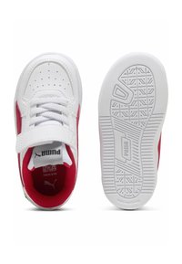 Zapatillas PUMA blancas con acentos laterales rojos, suela de goma texturizada, forro de malla, cierre de cordones y correa ajustable para un ajuste seguro.