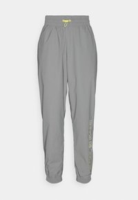 Graue Elastikhose mit Kordelzug, tapered Beinen und elastischen Bündchen. Verfügt über ein gelbes Logo an der Seite. Leichtes Material.
