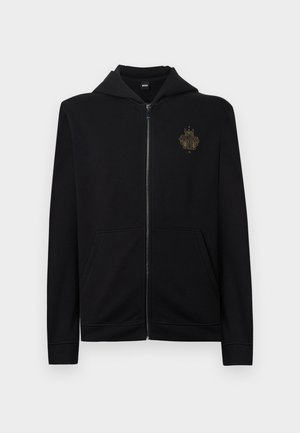 Čierna mikina na zips z bavlnenej zmesi s predným klokanie vreckom a kapucňou. Na ľavej strane na hrudi je zlaté vyšívané logo.
