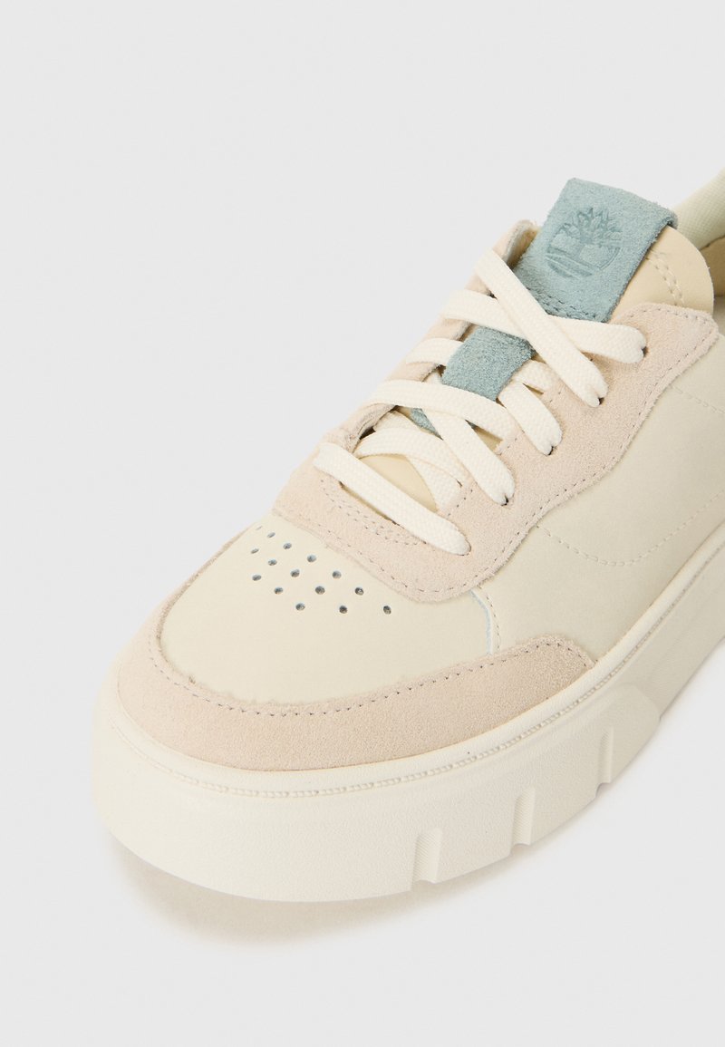 Sneaker in pelle beige con sovrapposizione in suede testurizzato, lacci crema e un accento azzurro chiaro sulla linguetta con logo. Area della punta perforata.