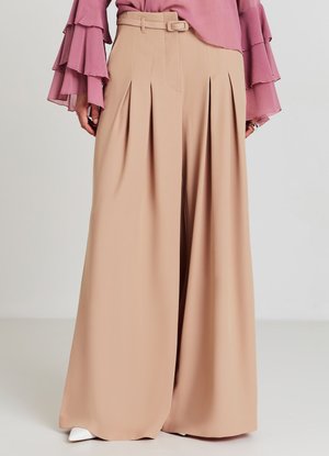 Wide-leg beige trousers with pleats and a matching belt, worn with a pink blouse featuring layered ruffle sleeves.