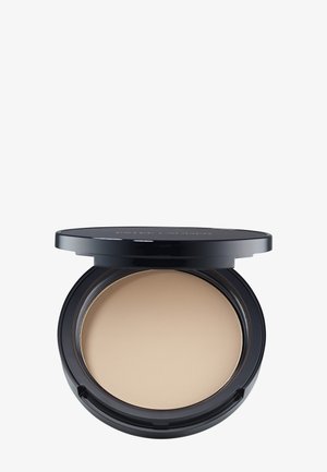 Trousse à maquillage noire compacte avec un fond de teint poudre pressée beige et un couvercle partiellement ouvert sur un fond blanc.
