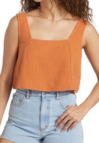 Orange cropped top made of textured fabric with a square neckline and wide straps, paired with high-waisted light blue denim shorts.