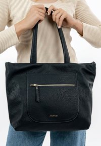 Black leather tote bag with textured surface and a zippered front pocket. Features two sturdy handles and gold-tone zipper accent.