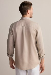 Beige-langärmliges Hemd aus leichtem Stoff, mit einem Button-Down-Kragen, hochrollbaren Ärmeln und einem abgerundeten Saum.