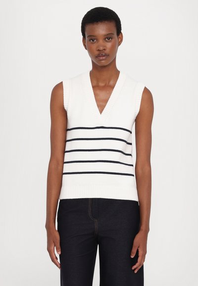 Bešėmis V formos megztinis kreminės spalvos su tamsiai mėlynomis horizontaliomis juostelėmis. Raštuotas apdailas ties apatine dalimi ir kaklu, prigludusi konstrukcija.