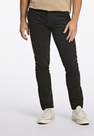 Mustat slim fit -housut, jotka on valmistettu puuvillasta sileällä pinnalla, joissa on klassinen viiden taskun malli, yhdessä valkoisten kangastennareiden kanssa.
