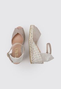 Sandalias de cuña beige con parte superior de ante, que cuentan con un diseño de punta abierta, tira en el tobillo y detalles de yute trenzado en el tacón.