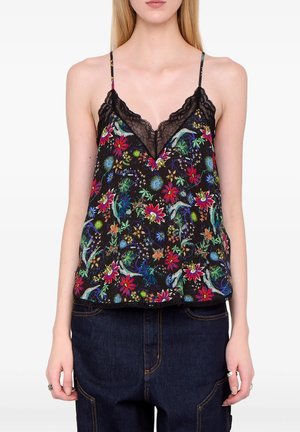 Frau trägt ein schwarzes, florales Spitzen-Camisole mit Spaghettiträgern und dunkelblaue Jeans.
