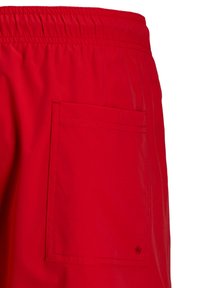 Short de bain rouge avec ceinture élastique et une poche arrière carrée comportant un petit trou de drainage dans le coin inférieur.