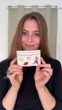 Portacarte bianco dal design minimalista, con toppe a forma di stella verde, labbra rosse e figura a fumetti viola. Dotato di tasca superiore.