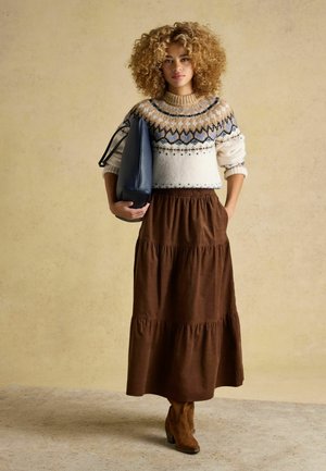 Knit sweater with a fair isle pattern in cream, brown, and blue, paired with a brown tiered maxi skirt and brown ankle boots.