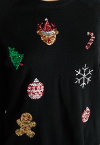 Pulover negru cu motive festive: brăduț verde, ornamente roșii și aurii, fulg de nea, om de turtă dulce și baston de cuker, toate decorate cu paiete.