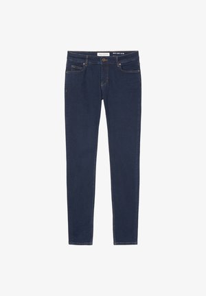 Camisa blanca de manga tres cuartos, jeans slim-fit azul marino y mocasines gruesos negros. Textura suave, diseño minimalista.
