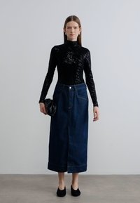 Μαύρο τοπ με παγιέτες και ζιβάγκο, συνδυασμένο με σκούρα τζιν φούστα midi μήκους. Το σύνολο διαθέτει μπροστινή σχισμή, πλαϊνές τσέπες και μαύρα παπούτσια.