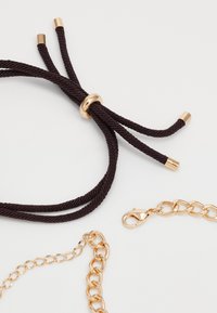 Braided dark brown rope with a gold metal accent, alongside a gold chain with a lobster clasp and rounded links.