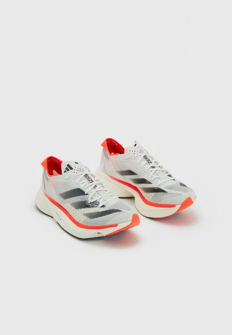 Witte en grijze sportschoenen met zwarte strepen, lichtgewicht mesh bovenkant, feloranje accenten, gevoerd kraag en textuurzool.