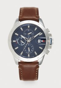 Montre chronographe pour homme avec un cadran bleu marine, un boîtier en acier inoxydable argenté, un bracelet en cuir marron et un affichage de la date à 3 heures.