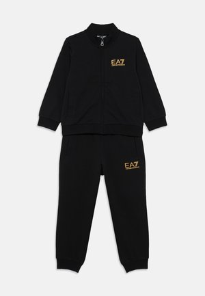 Schwarzes Trainingsanzug-Set bestehend aus einer Jacke mit Reißverschluss und passenden Hosen, gefertigt aus weichem Stoff mit goldenen EA7-Logo-Akzenten auf beiden Teilen.