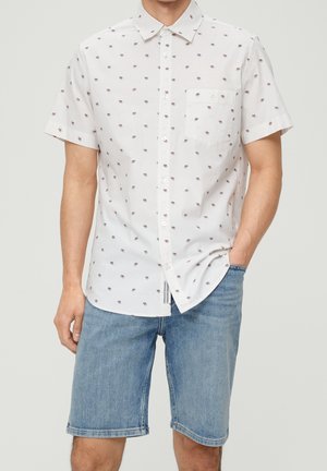 Kurzärmliges, weißes Hemd mit Knöpfen, das ein florales Muster in Rot und Blau aufweist, mit einer Brusttasche, kombiniert mit hellblauen Jeansshorts.