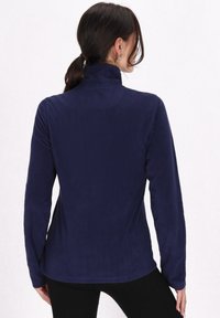 Navy blue fleece-pullover med høj krave, lange ærmer og en glat tekstur. Bagsiden har en buet søm for ekstra design.