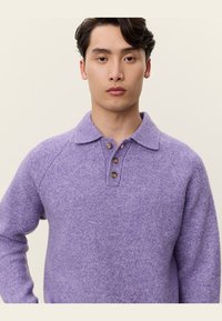 Μωβ πουλόβερ από μαλλί τύπου πόλο με γιακά, τρία καφέ κουμπιά και υφή, διαθέτοντας ραγλανικά μανίκια για επιπλέον άνεση.