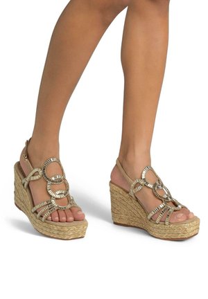 Sandali con zeppa e suola intrecciata in juta, dettagli circolari in tonalità oro, cinturini alla caviglia regolabili e colore beige neutro. Design open-toe.